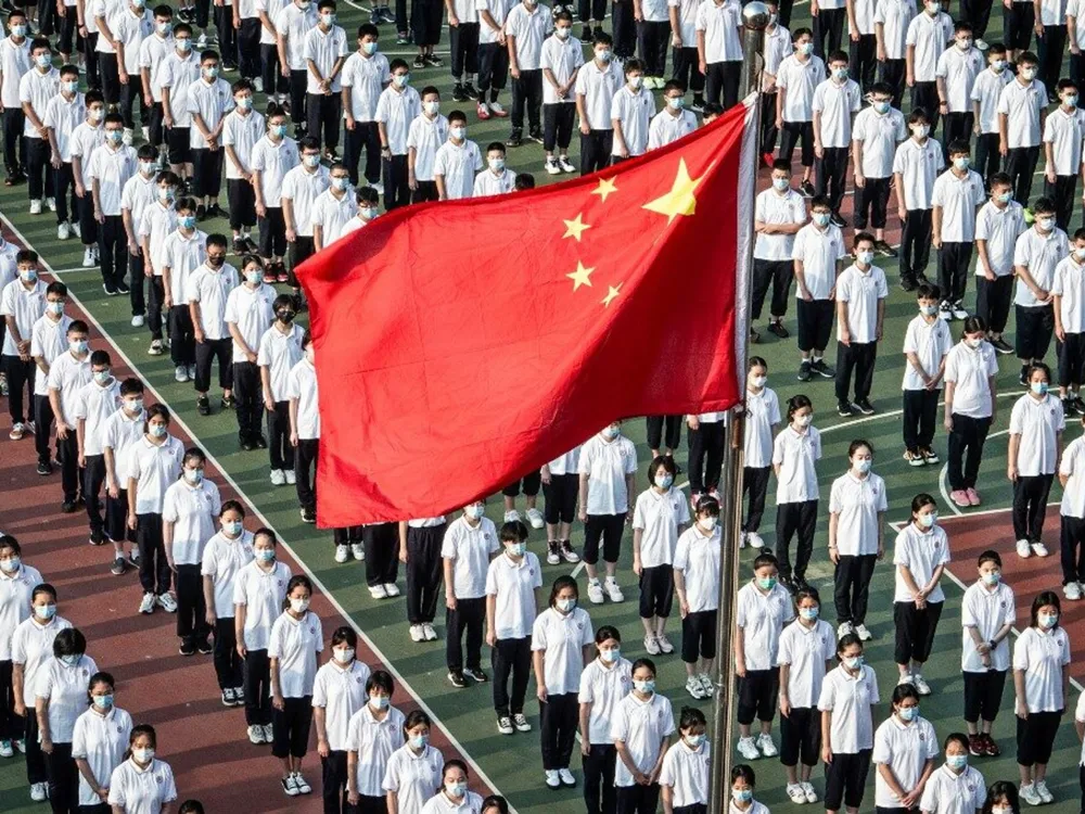นักเรียนเข้าร่วมพิธีเคารพธงชาติในโรงเรียนจีน พร้อมธงชาติจีนกลางสนาม