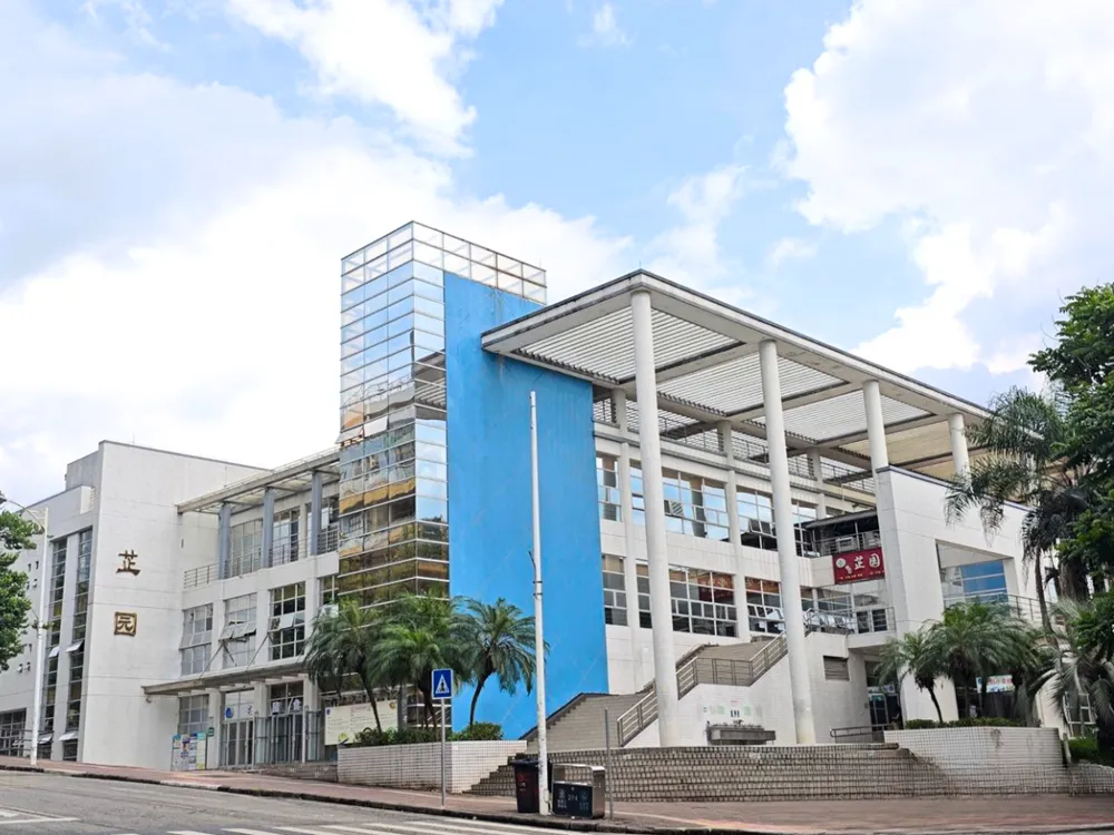 อาคารสมัยใหม่สีขาว–น้ำเงินของ South China Agricultural University พร้อมเสากลมสูง หน้าต่างกระจก และต้นปาล์มรายล้อม