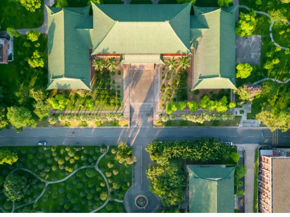 ภาพถ่ายมุมสูงของอาคารหลัก South China Agricultural University หลังคาสีเขียว รายล้อมด้วยสวนและต้นไม้เขียวชอุ่ม