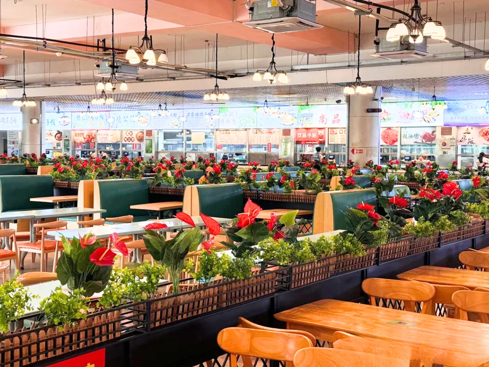 บรรยากาศโรงอาหารสมัยใหม่ของ South China Agricultural University โต๊ะไม้ เก้าอี้บูธเบาะสีเขียว พร้อมร้านอาหารและป้ายเมนูภาษาจีน