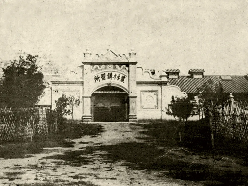 ภาพถ่ายขาวดำของอาคารสถาปัตยกรรมจีนโบราณที่มีซุ้มประตูโค้ง พร้อมป้ายชื่อสถาบัน