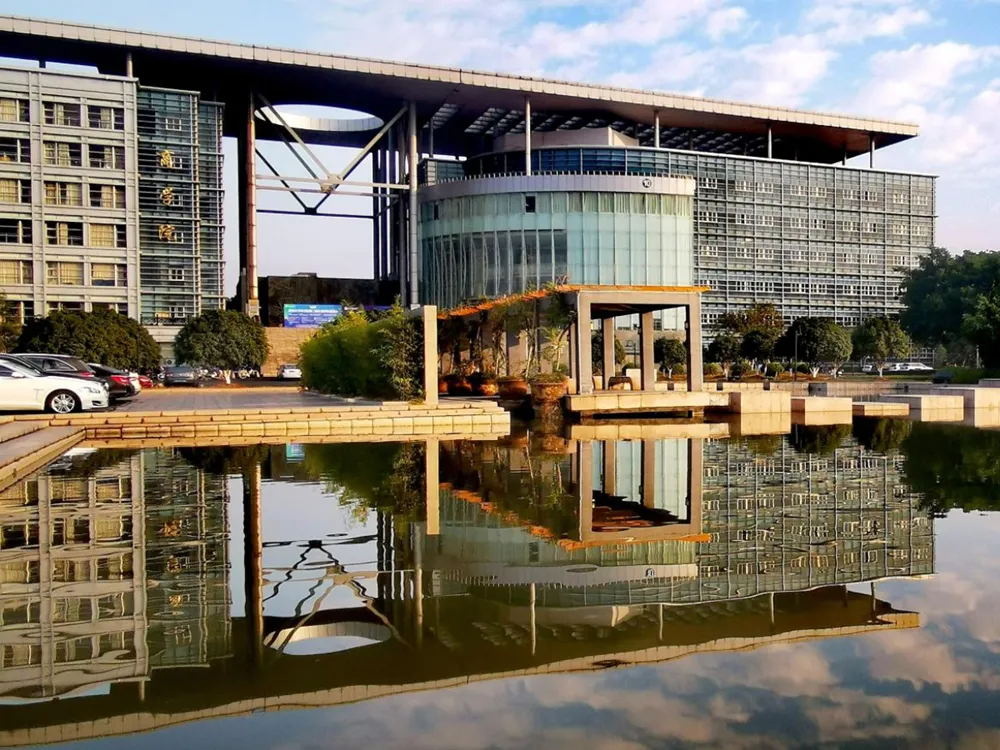 อาคารกระจกทรงร่วมสมัยของ Wenzhou University of Technology สะท้อนภาพในสระน้ำด้านหน้า