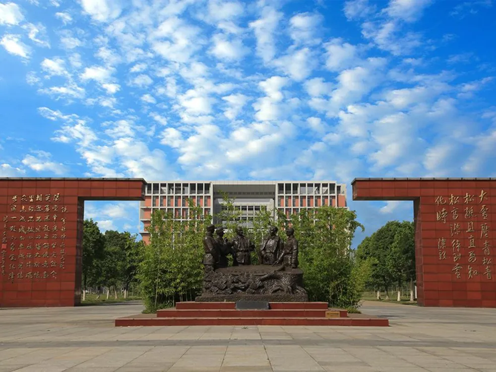 อนุสาวรีย์กลางลานมหาวิทยาลัย Yancheng Institute of Technology รูปปั้นบรอนซ์และกำแพงแดงจารึกอักษรจีน