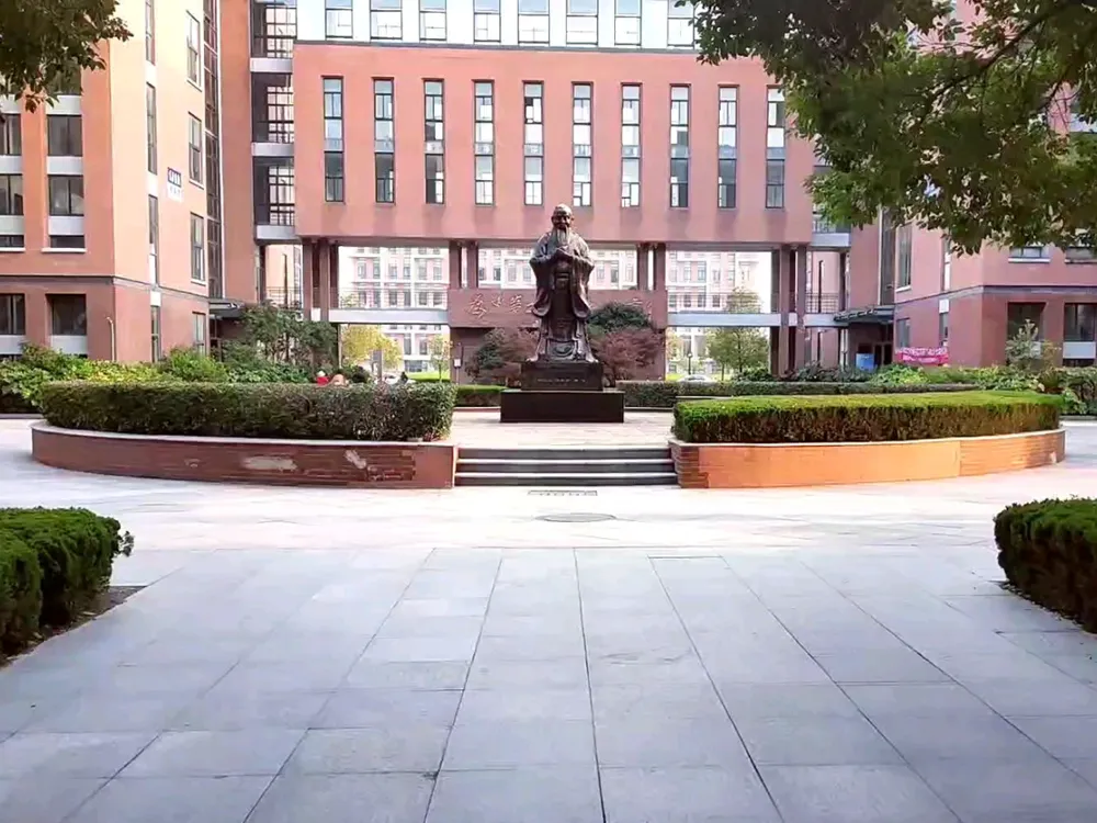ลานกลางมหาวิทยาลัย Yancheng Institute of Technology พร้อมรูปปั้นบุคคลในชุดโบราณและสวนหย่อม