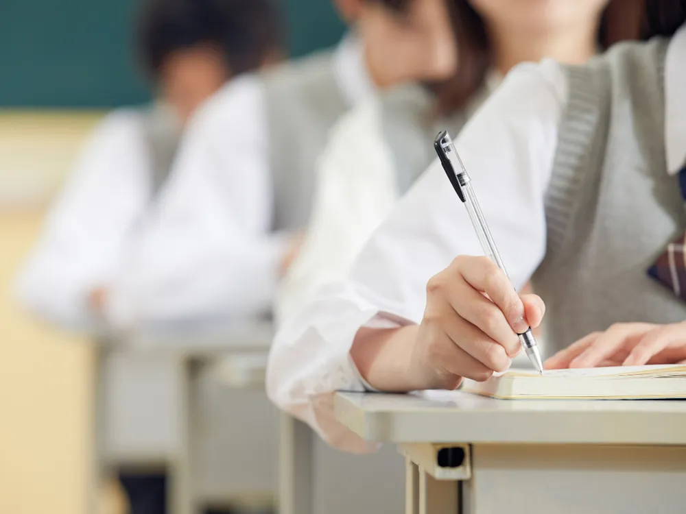 นักเรียนสวมชุดยูนิฟอร์ม เขียนบันทึกในสมุดระหว่างการเรียนคอร์ส CSCA Math
